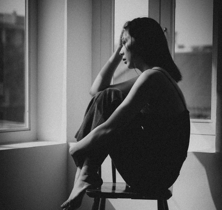woman sitting looking out window sad